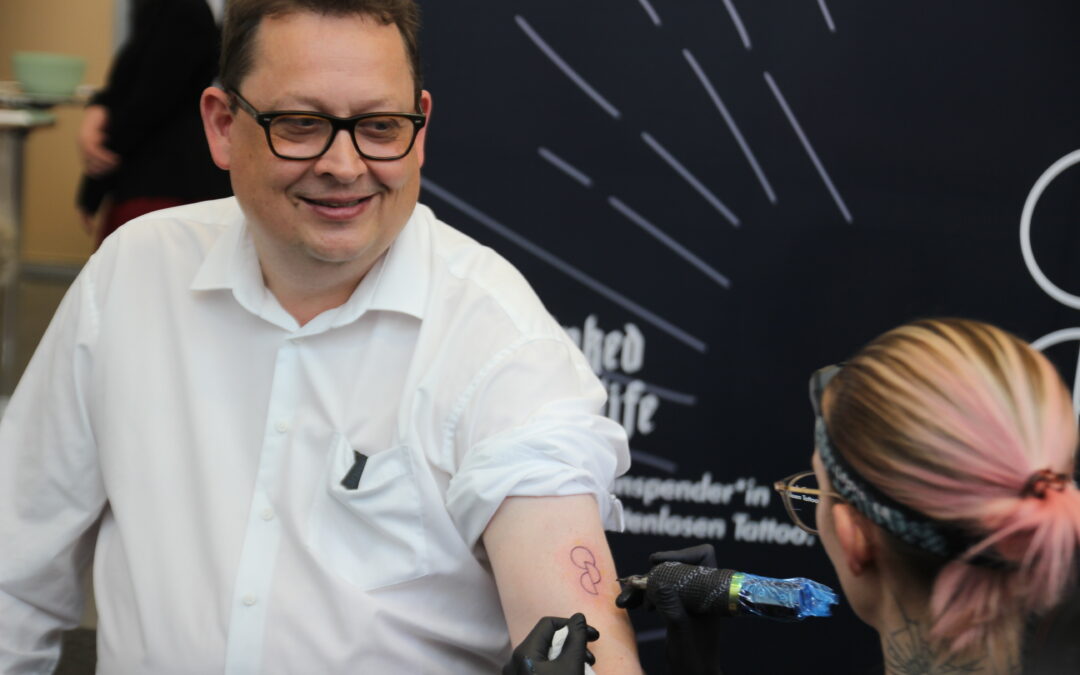 Stefan Schwartze lässt sich im Bundestag das Tattoo Opt.Ink stechen